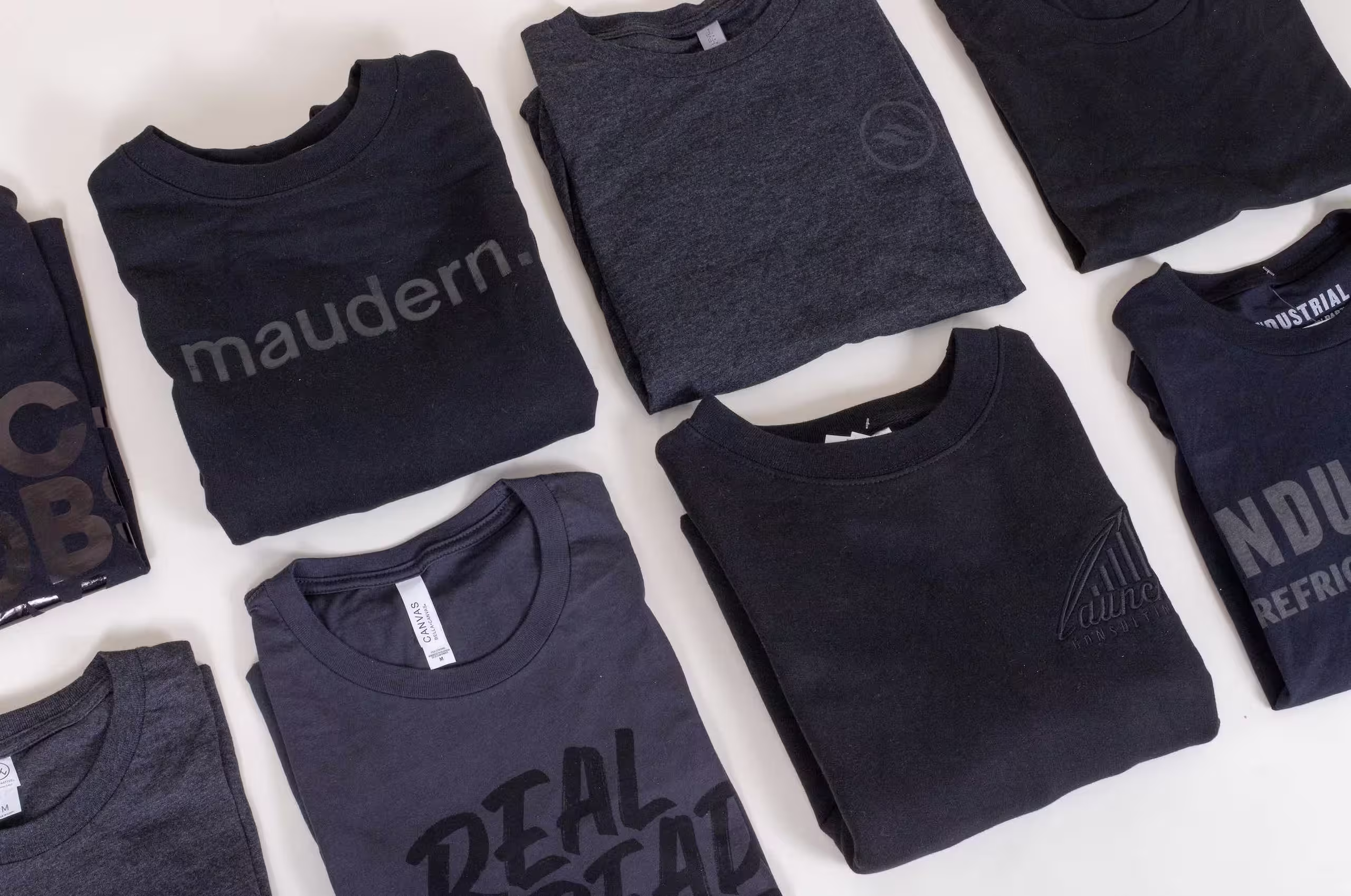 two rows of folded black t-shirts with black imprint
