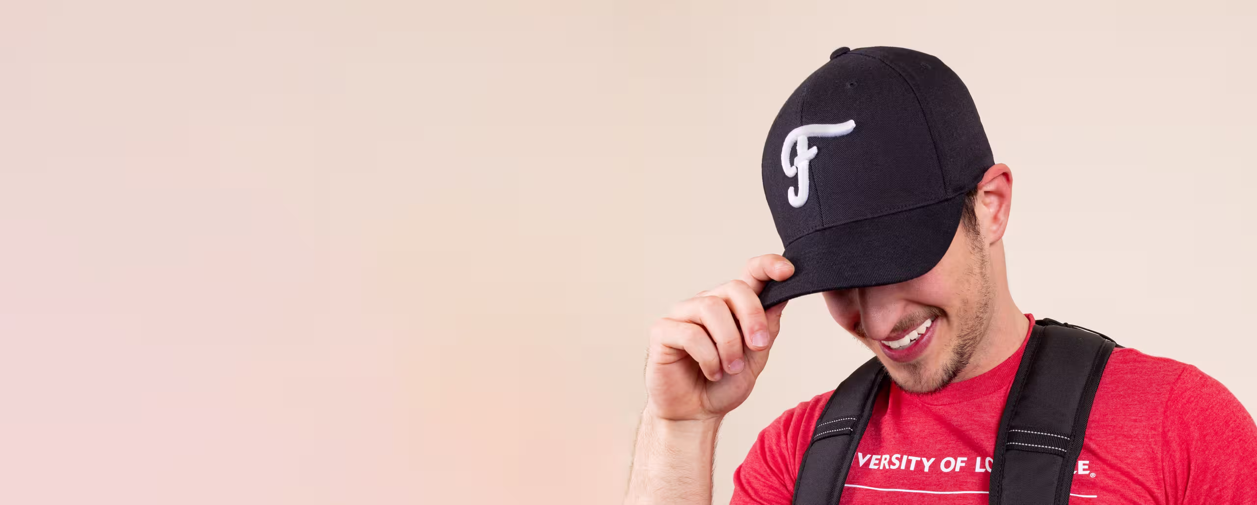 Man wears black hat with white puff embroidery of an "F" logo on it