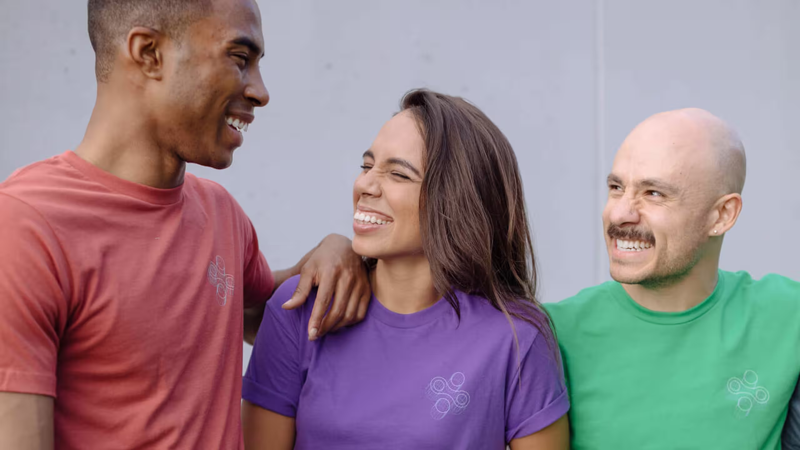 three people wearing three different color t-shirts: red, purple, and green