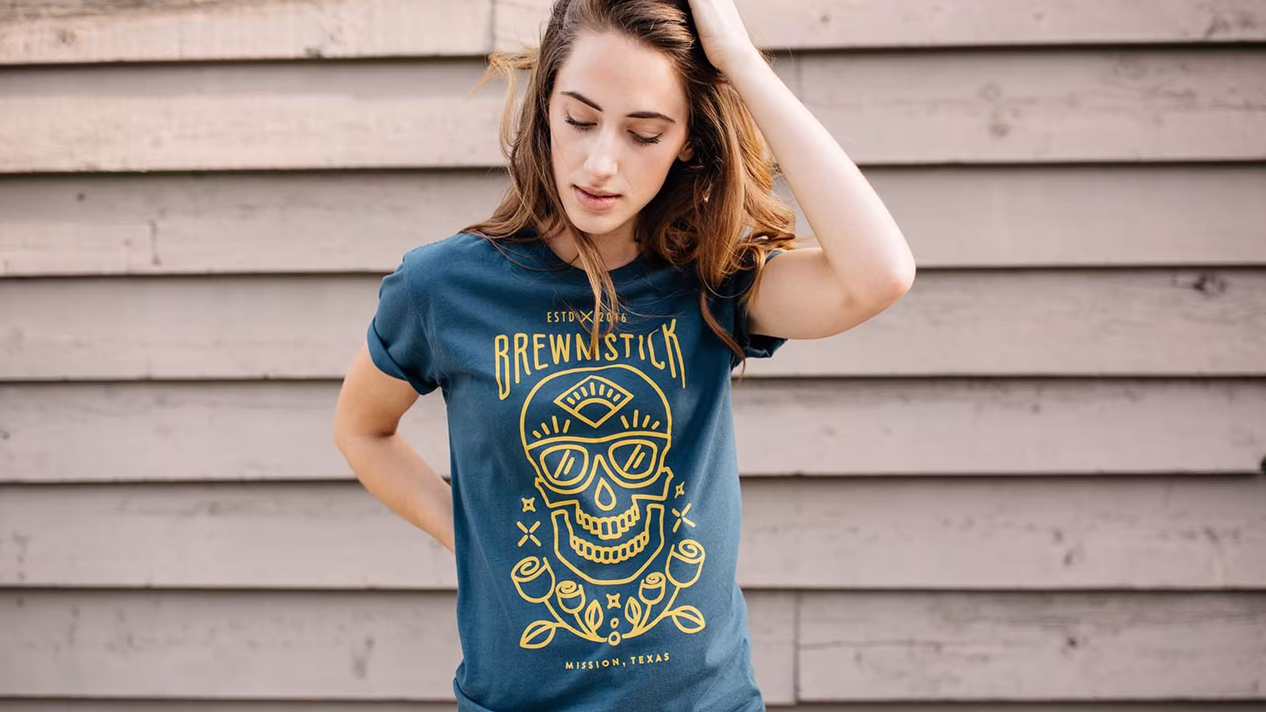women wearing a green-blue shirt with a yellow outline of skull and roses