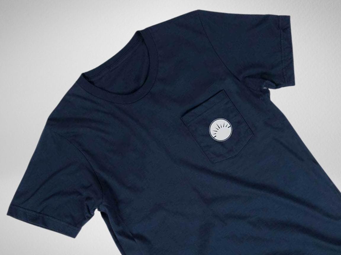 Navy pocket t-shirt with white circle logo against a white background Navy pocket t-shirt with white circle logo against a white background