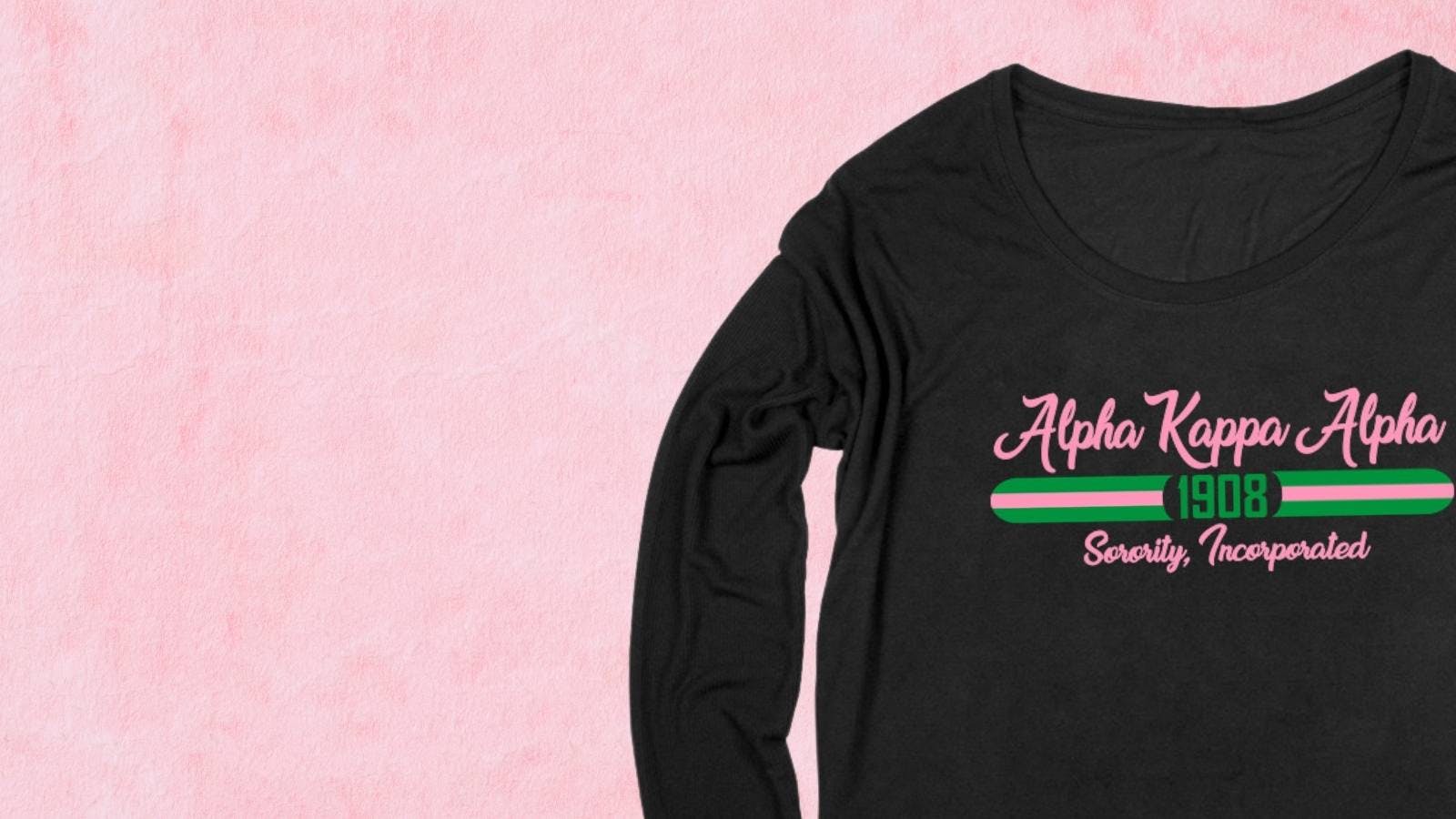 Black sorority long sleeve t-shirt with pink and green text on a pink background Black sorority long sleeve t-shirt with pink and green text on a pink background